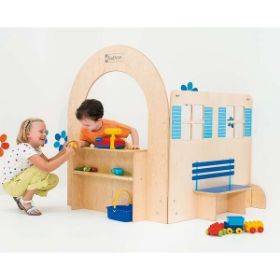 Η πρόσοψη της εισόδου σπιτιού Nathan 372054 σε συνδυασμό με άλλα έπιπλα της ίδιας σειράς τοποθετημένα σε εκπαιδευτικό χώρο και παιδιά που παίζουν δημιουργικά παιχνίδια μίμησης..