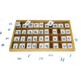 Ανοιχτή ξύλινη κασετίνα με πολλά χωρίσματα που περιέχουν ελληνικά μαγνητικά γράμματα, τοποθετημένη σε λευκό φόντο.