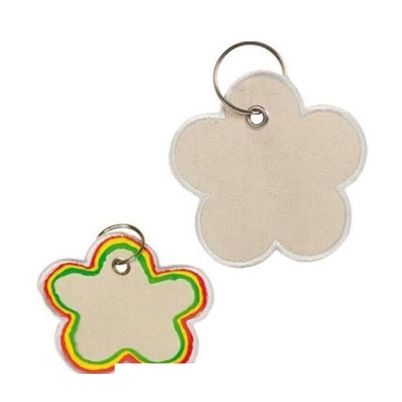 Το λευκό υφασμάτινο μπρελόκ σε σχήμα λουλουδιού Beleduc 51108 με τον μεταλλικό κρίκο και ένα ζωγραφισμένο υφασμάτινο λουλούδι.